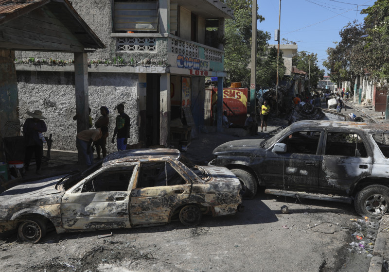 Haitianos pasan junto a vehículos incendiados