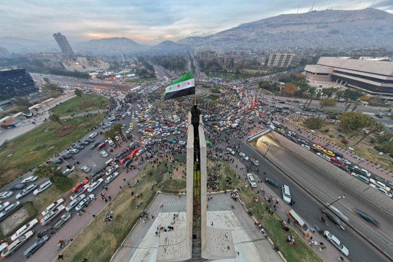 Un hombre sirio ondea la bandera siria de la era de la independencia en la plaza central de los Omeyas de Damasco.