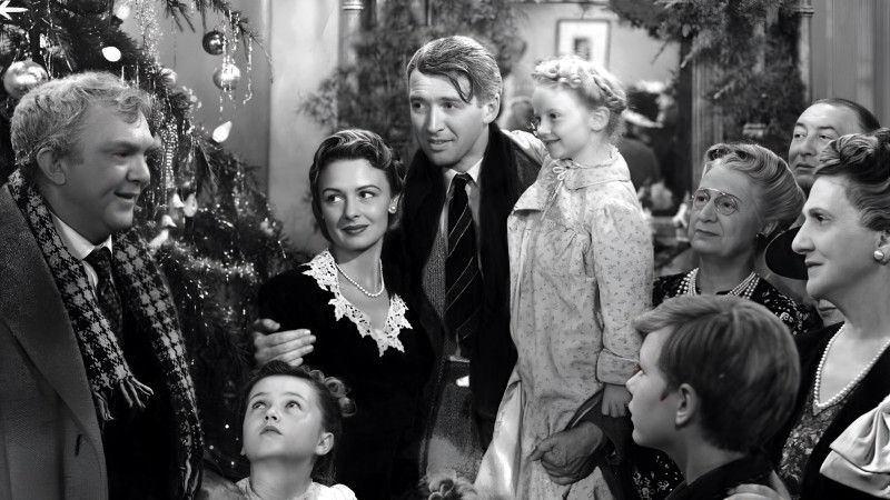 La emotiva escena culminante de '¡Qué bello es vivir!' (1946), dirigida por Frank Capra, donde George Bailey (James Stewart), tras recuperar la esperanza en la vida, celebra la Navidad rodeado de su esposa Mary (Donna Reed), sus hijos y los vecinos que acuden a su hogar para apoyarlo. Este icónico momento simboliza la importancia de la comunidad, la solidaridad y el amor familiar, capturando la esencia del espíritu navideño. Herbert Dorfman/Corbis vía Getty Images.