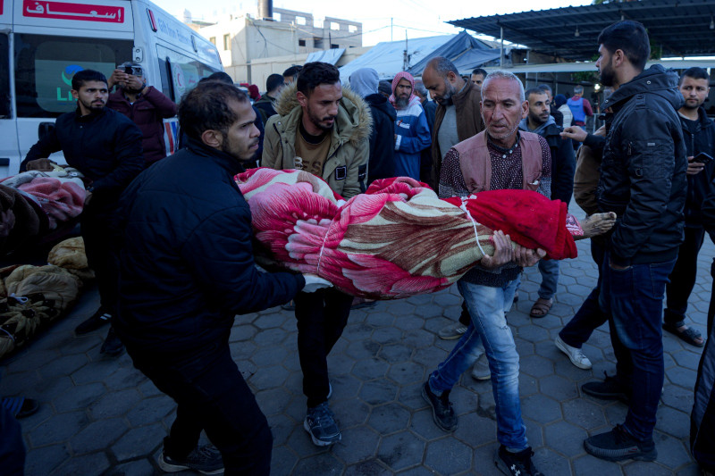 Palestinos llevan el cuerpo de un familiar muerto en el bombardeo israelí de la Franja de Gaza en un hospital de Deir al-Balah,  ayer domingo.