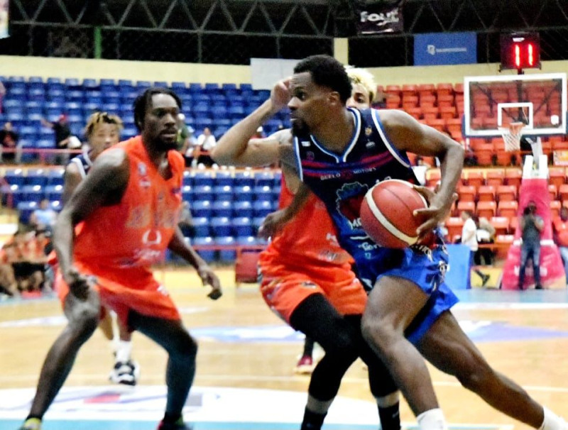 Juan Miguel Suero, de La Matica, se dirige hacia el canasto ante la mirada de Emmitt Williams, de La Villa en el tercer partido de la final del torneo superior de La Vega.