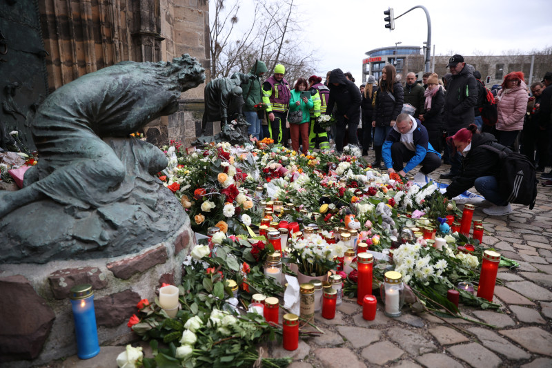 La gente deposita flores y velas en el lugar de un ataque con coche en un mercado navideño en Magdeburgo, este de Alemania, el 21 de diciembre de 2024, que provocó varias muertes y decenas de heridos.