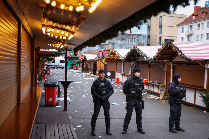 Se ven escombros y puestos cerrados mientras agentes de policía se encuentran en el lugar de un ataque con un coche en un mercado navideño en Magdeburgo, este de Alemania, el 21 de diciembre de 2024, que provocó varias muertes y decenas de heridos.