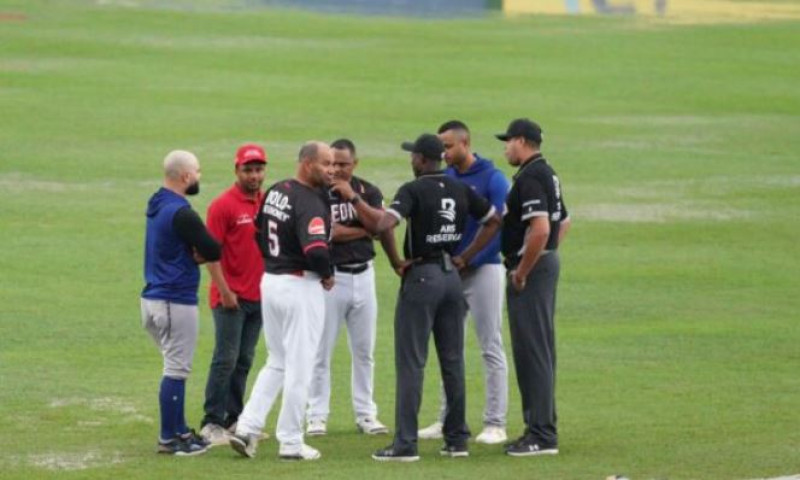 Los árbitros, junto a los mánager Albert Pujols y Gilbert Gómez, conversan en el campo de juego diezmado por la lluvia.