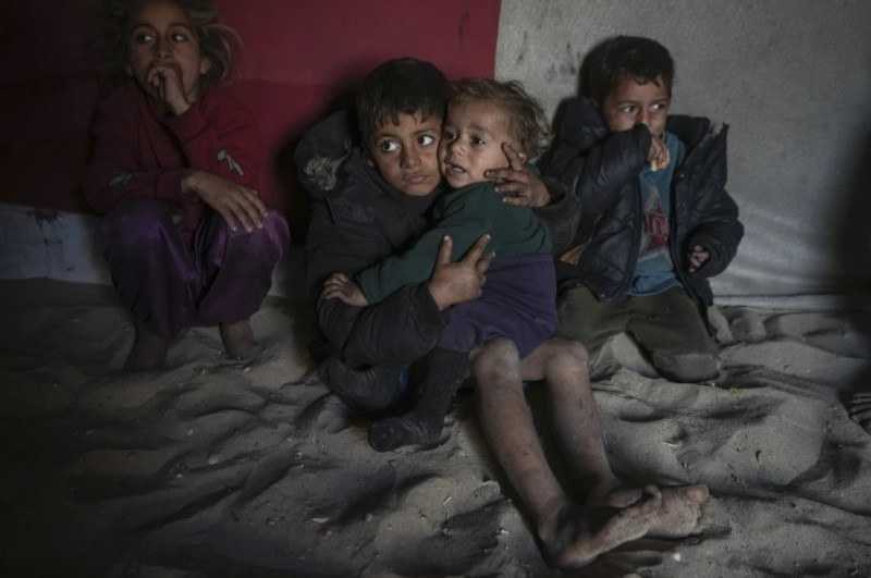 El palestino Tamim Marouf, de 6 años, sentado en la tienda de campaña de su familia junto a su hermana Hala, de 10 años, y su hermano Malek, de 4 años, en un campamento para desplazados.