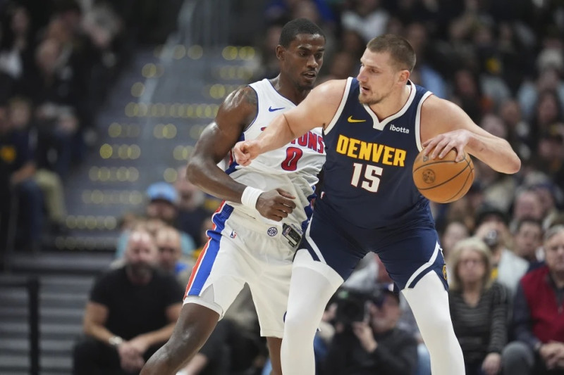 El pívot de los Nuggets de Denver, Nikola Jokic, al frente, busca pasar el balón mientras el pívot de los Pistons de Detroit, Jalen Duren, defiende en la primera mitad de un partido.