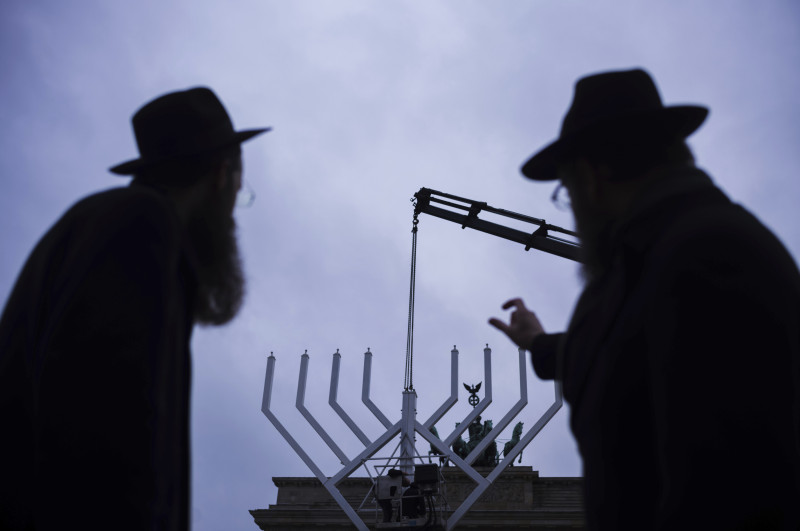 El rabino Yehuda Teichtal, a la derecha, y el rabino Shmuel Segal, a la izquierda, observan el montaje de una Menorah gigante de Hanukkah por el Centro Educativo Judío Jabad antes de la festividad judía de Hanukkah, frente a la Puerta de Brandenburgo en la Pariser Platz en Berlín, Alemania, el lunes 23 de diciembre de 2024. (AP foto/Markus Schreiber)