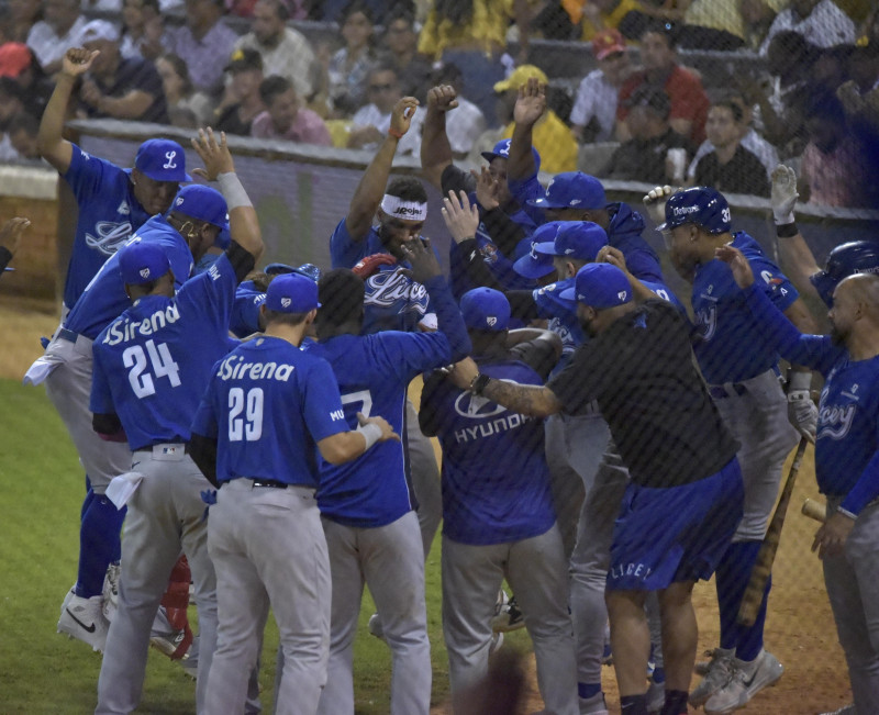 Varios peloteros del Licey rodean a Jorge Alfaro luego de conectar su vuelacercas en el éxito de los azules sobre las Aguilas en el estadio Cibao.