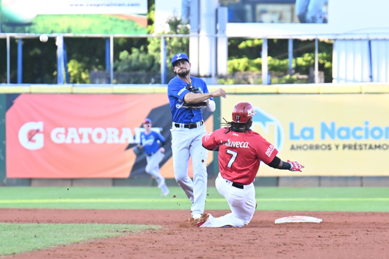 Gustavo Núñez, del Licey, fuerza a Jean Segura, del Escogido, en el partido celebrado el lunes en el estadio Quisqueya Juan Marichal.