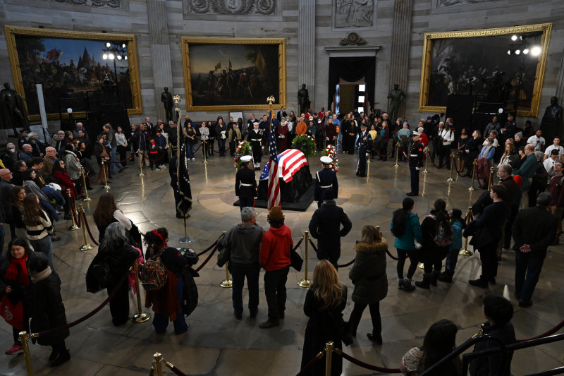 El público observa el ataúd cubierto con la bandera del expresidente Jimmy Carter