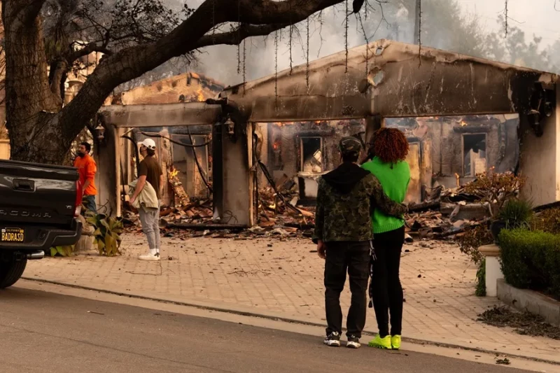 Personas observan una casa afectada por un incendio, en Altadena, California (Estados Unidos).