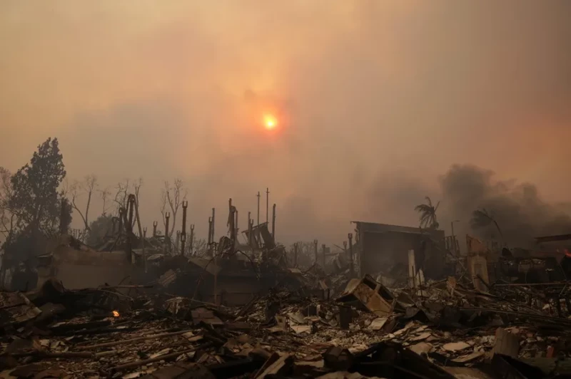 El sol brilla a través del humo sobre las ruinas de las casas del incendio forestal.