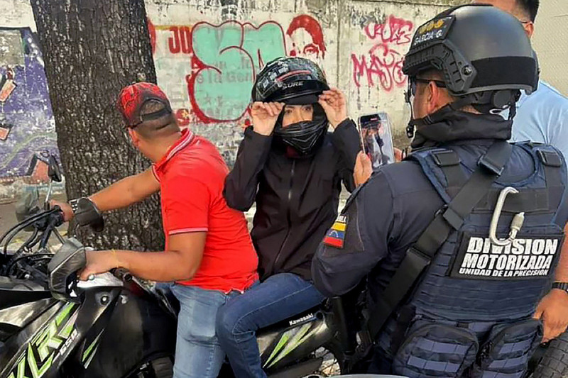 María Corina Machado siendo filmada por un oficial de la Policía Nacional después de pronunciar un discurso durante una manifestación convocada por la oposición en vísperas de la toma de posesión presidencial, ayer en Caracas.