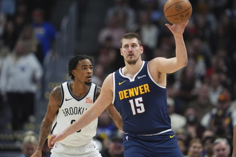 Nikola Jokic (15), de los Nuggets de Denver, recibe un pase, con la marca defensiva de Nic Claxton, de los Nets de Brooklyn, en la primera mitad del juego de baloncesto de la NBA.