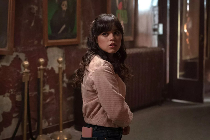 Jenna Ortega en Scream VI (2023), donde da vida a Tara Carpenter, la hermana menor de Sam. Su personaje, víctima de los ataques de Ghostface, se convierte en uno de los pilares emocionales de la película. A través de Tara, Ortega combina vulnerabilidad con valentía, aportando un enfoque fresco y relevante a la saga de terror, mientras establece una dinámica de fuerte vínculo familiar con su hermana en la trama. PHILIPPE BOSSÉ/PARAMOUNT PICTURES