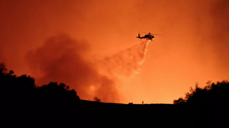 Un helicóptero descarga agua sobre el incendio de Palisades, entre Mulholland Drive y el barrio de Encino, el 10 de enero de 2025 en Los Ángeles, al oeste de EEUU