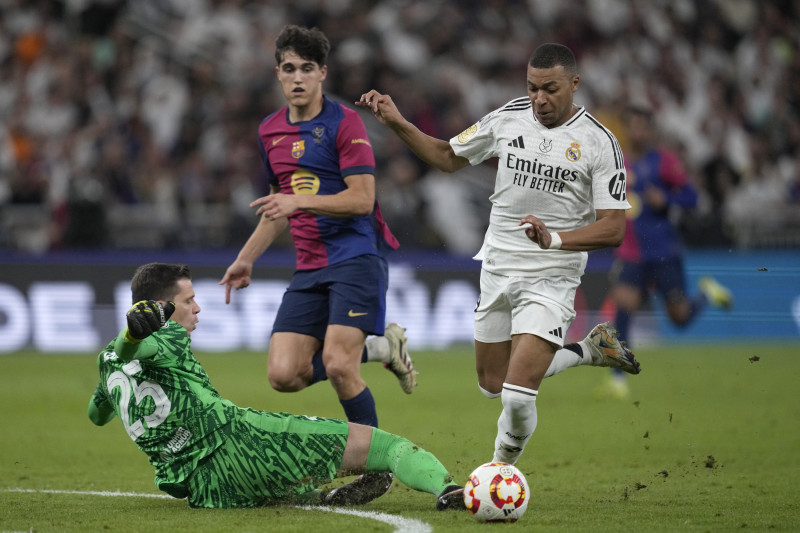 El portero del Real Madrid, Kylian Mbappé (derecha), disputa el balón con el portero del Barcelona, ​​Wojciech Szczesny