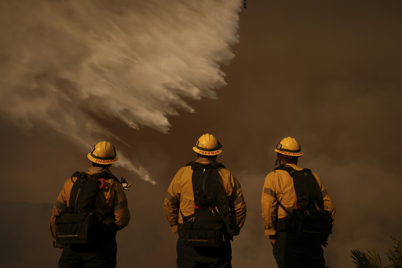 Los bomberos observan las gotas de agua que caen sobre el incendio Palisades