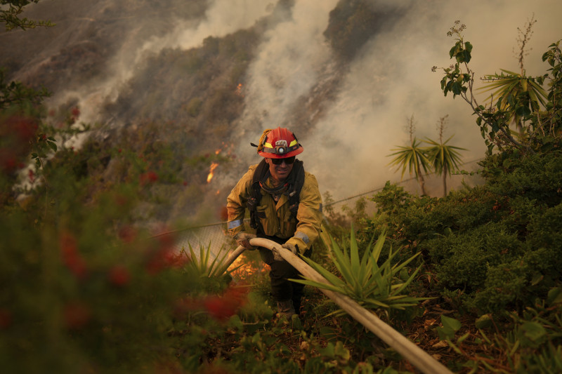 Un bombero instala una manguera mientras combate el incendio Palisades