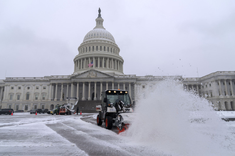 Una máquina quitanieves limpia el área mientras la nieve cubre el Capitolio