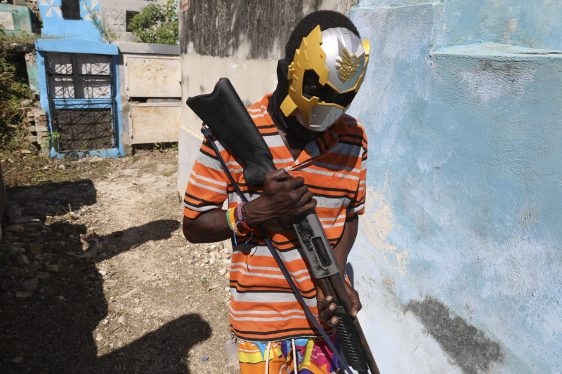 Un miembro de una banda, con el rostro cubierto por una máscara, posa para una foto en el Cementerio Nacional durante la conmemoración del Día de los Muertos en honor a los espíritus del vudú haitiano Baron Samedi y Gede, en Puerto Príncipe, Haití, el 1 de noviembre de 2024.