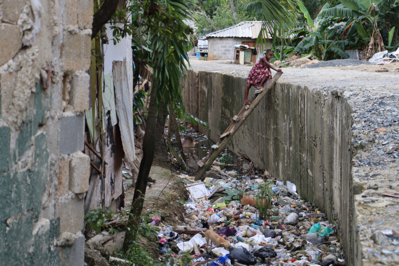 Una niña trepa por una escalera rudimentaria para cruzar una cañada en Pantoja