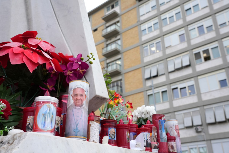 se colocan velas a los pies de una estatua del papa Juan Pablo II en el exterior del hospital Gemelli,