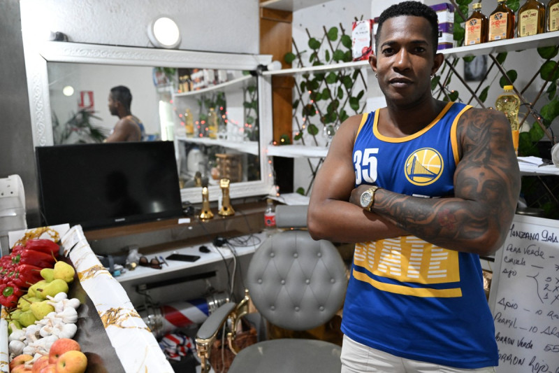 El cubano Jorge Zamora posa para un retrato en la barbería y tienda de comestibles donde trabaja en Montevideo el 27 de febrero de 2025.