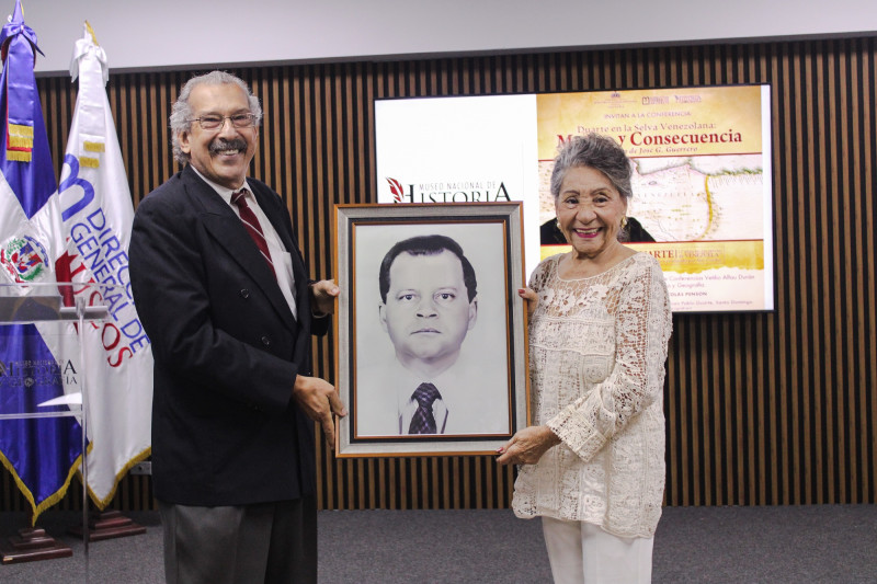 José G. Guerrero Sánchez, director del Museo Nacional de Historia y Geografía, hace entrega a Eulalia Flores del reconocimiento póstumo a Pedro Julio Santiago Canario, exdirector de la institución museística.
