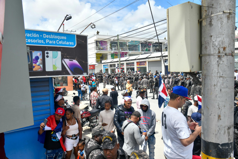 Manifestantes con banderas en mano mientras los Policías Nacionales se mantienen en formación.