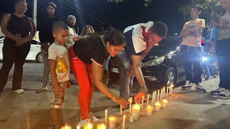 Mujer encendiendo velas en homenaje a víctimas del 8 de abril.