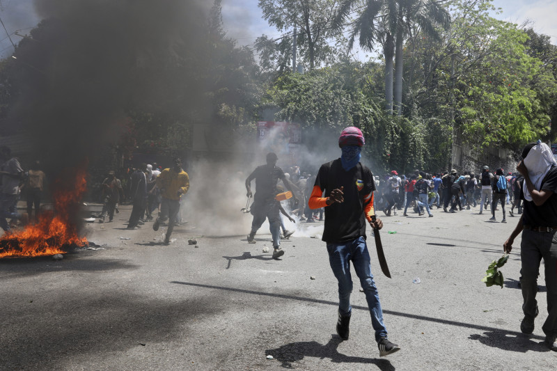Manifestantes corren para protegerse de los gases lacrimógenos