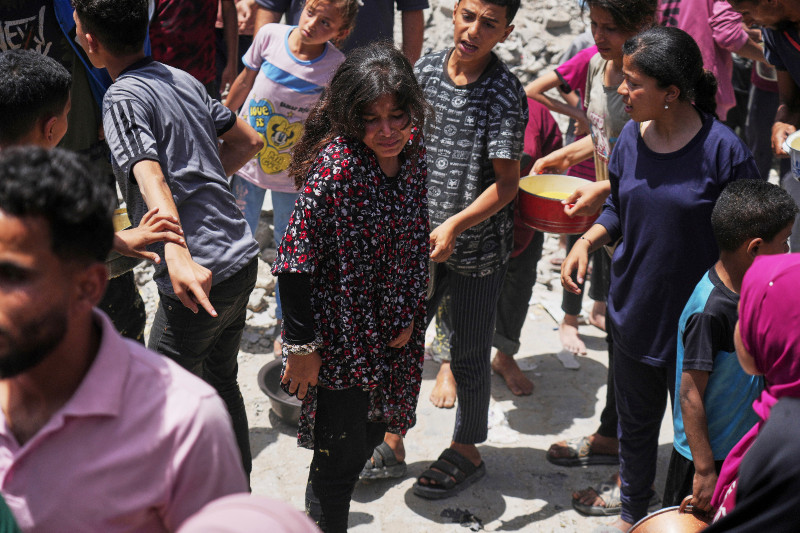 Palestinos hacen fila para conseguir comida donada en una cocina comunitaria en Jabalia, en el norte de la Franja de Gaza, el lunes 19 de mayo de 2025.