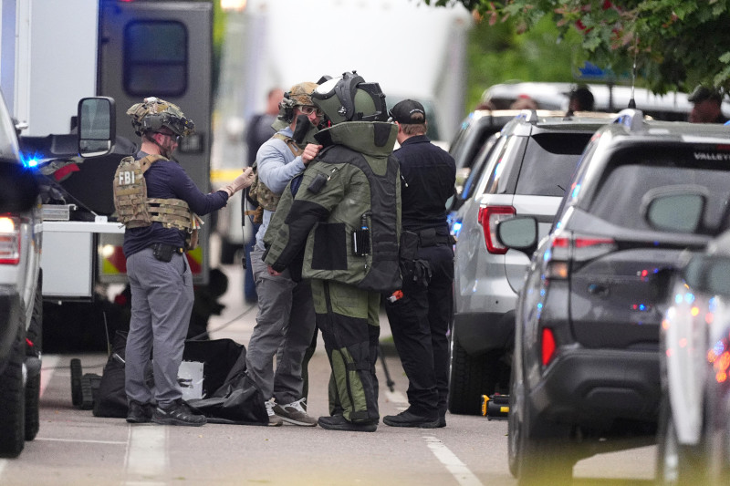 Agentes policiales se colocan equipo de protección para investigar un ataque en el centro comercial Pearl Street Mall, ayer en Boulder.