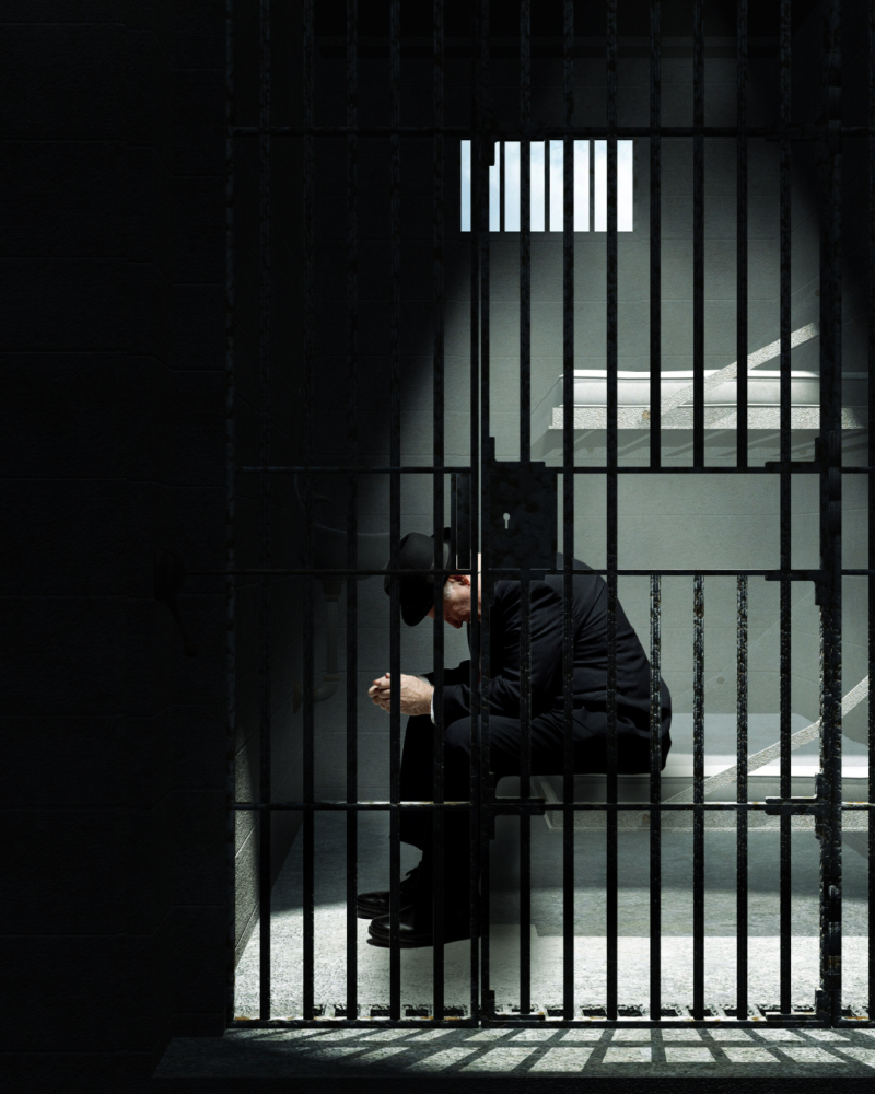 Imagen ilustrativa de un hombre cavizbajo encerrado en una cárcel.