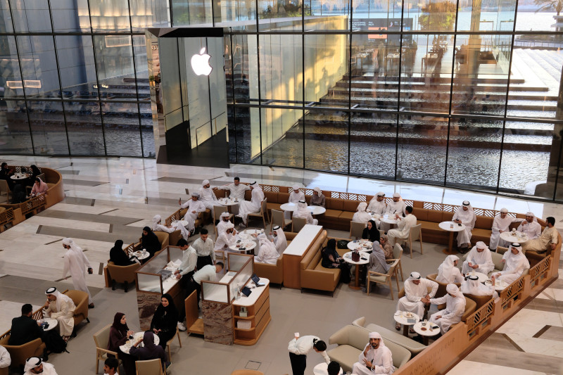 Personas sentadas en una cafetería frente a la Apple Store en Dubái el 8 de mayo de 2025. (Foto de Giuseppe CACACE / AFP)