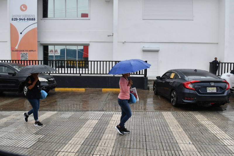 Personas caminan mientras se protegen de las lluvias