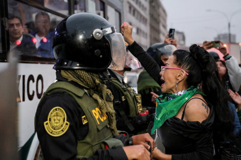 Una integrante de un grupo feminista grita consignas junto a un agente antidisturbios mientras participa en una protesta contra el nuevo presidente de Perú, José Jeri, frente al Congreso Nacional en Lima el 10 de octubre de 2025.