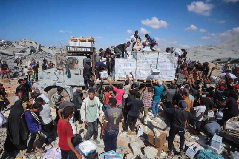 Palestinos reciben paquetes de alimentos tras la entrada de camiones de ayuda desde el cruce de Karem Abu Salem, en Khan Yunis, al sur de la Franja de Gaza, el 12 de octubre de 2025, mientras se mantiene el alto el fuego entre Israel y las facciones palestinas en el territorio asediado.