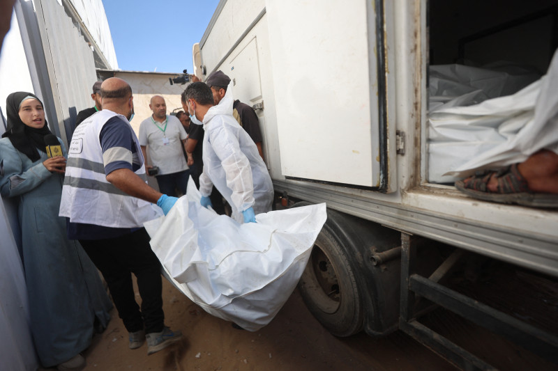 Trabajadores de la morgue descargan los cuerpos de palestinos que habían estado bajo custodia israelí, tras ser transportados en vehículos de la Media Luna Roja y camiones refrigerados, al hospital Nasser de Khan Yunis, en el sur de la Franja de Gaza, el 15 de octubre de 2025. Según el acuerdo de alto el fuego negociado por el presidente estadounidense, Israel debía entregar los cuerpos de 15 palestinos por cada israelí fallecido que regresara.