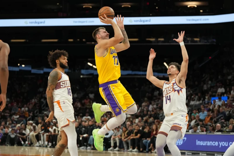 El alero de los Lakers Luka Dončić lanza el balón sobre Isaiah Livers y Koby Brea de los Suns en el encuentro de pretemporada del 14 de octubre del 2025.
