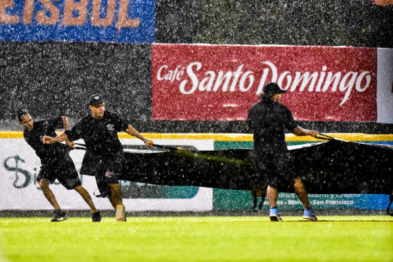Momentos en que trabajadores colocan la lona en el estadio Julián Javier, minutos después el choque fue suspendidos por las fuertes lluvias caídas en esa localidad.