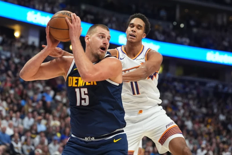 Nikola Jokic, de los Nuggets, captura un rebote mientras Oso Ighodaro, de los Suns, defiende en la primera mitad de un juego de la NBA el 25 de octubre de 2025, en Denver.