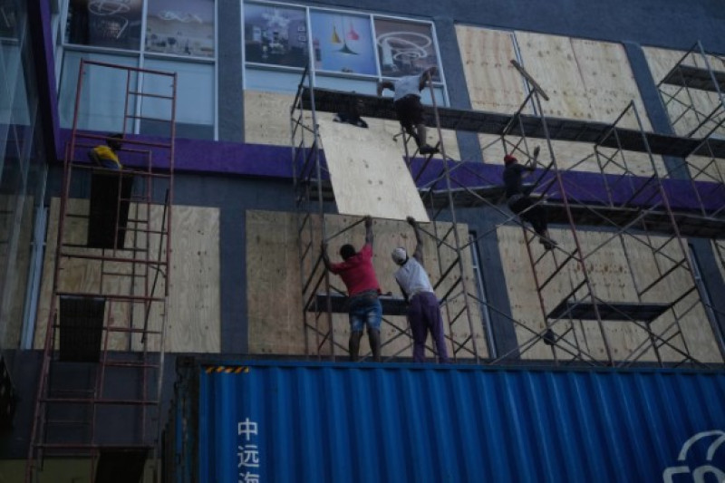 Trabajadores tapian los escaparates de sus tiendas antes de la llegada prevista del huracán Melissa a Kingston, Jamaica, el domingo 26 de octubre de 2025.
