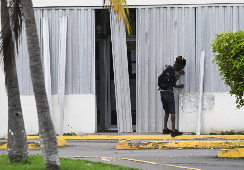 Un hombre instala contraventanas para tormentas en un negocio en preparación para la llegada del huracán Melissa a Portmore, parroquia de St. Catherine, Jamaica, el 25 de octubre de 2025.