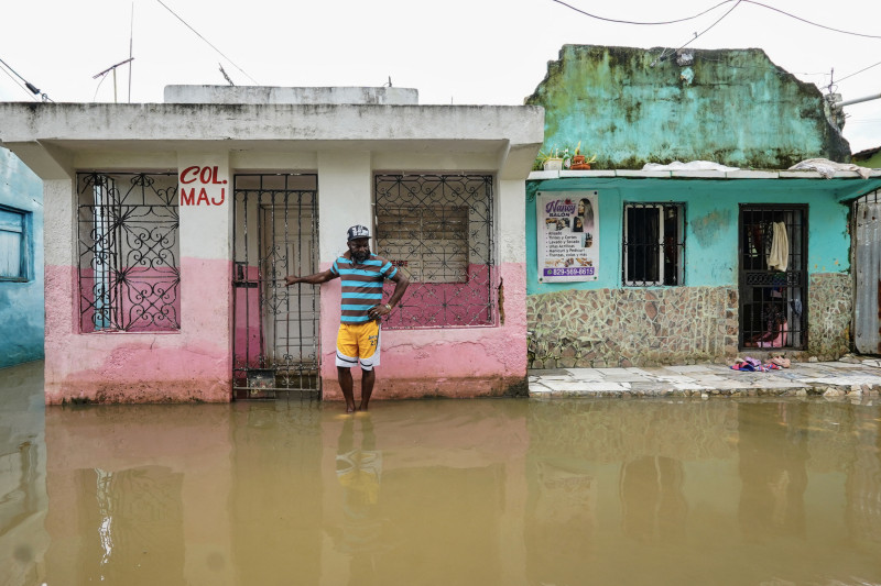 Un hombre se encuentra junto a una casa en una calle inundada antes de la llegada del huracán Melissa al barrio Las Cucarachas en Santo Domingo, República Dominicana, el 28 de octubre de 2025.