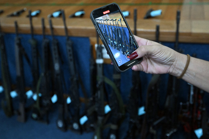 Un agente de policía graba con su teléfono móvil un vídeo de los fusiles de asalto incautados durante la Operación Contención, mostrado en una rueda de prensa en la sede de la Policía Civil de Río de Janeiro, Brasil, el 29 de octubre de 2025.