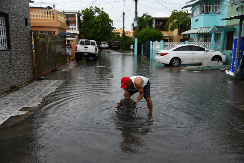 Un hombre saca de entre el agua pertenencias personales arrastradas por los aguaceros.