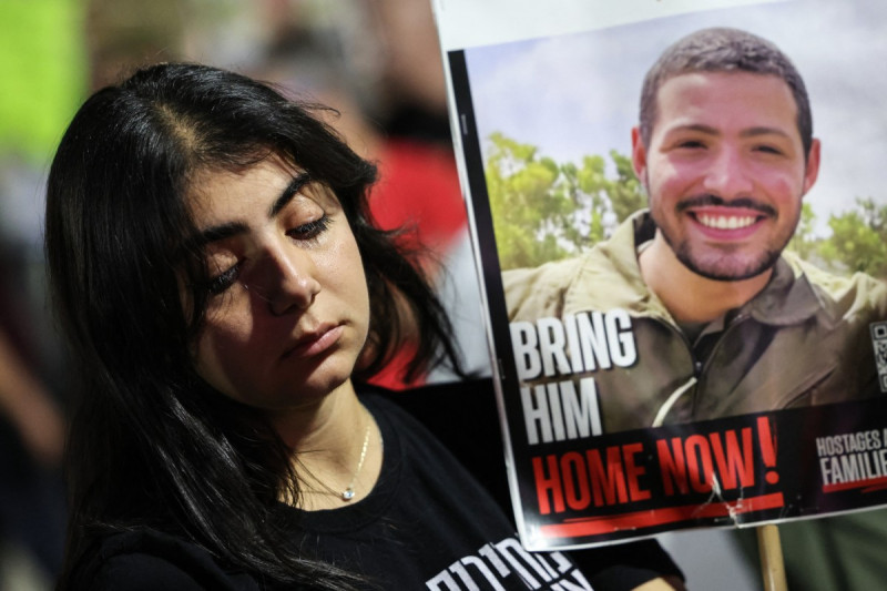Una mujer que sostiene un retrato de un rehén israelí reacciona durante una manifestación organizada por familiares de rehenes.