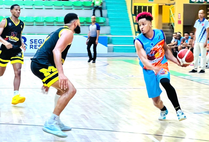 Raymer Santana, de los Correcaminos de Quisqueya, avanza en dribleo con el balón defendido por Dayker Cedano, de los Titanes de Miramar.